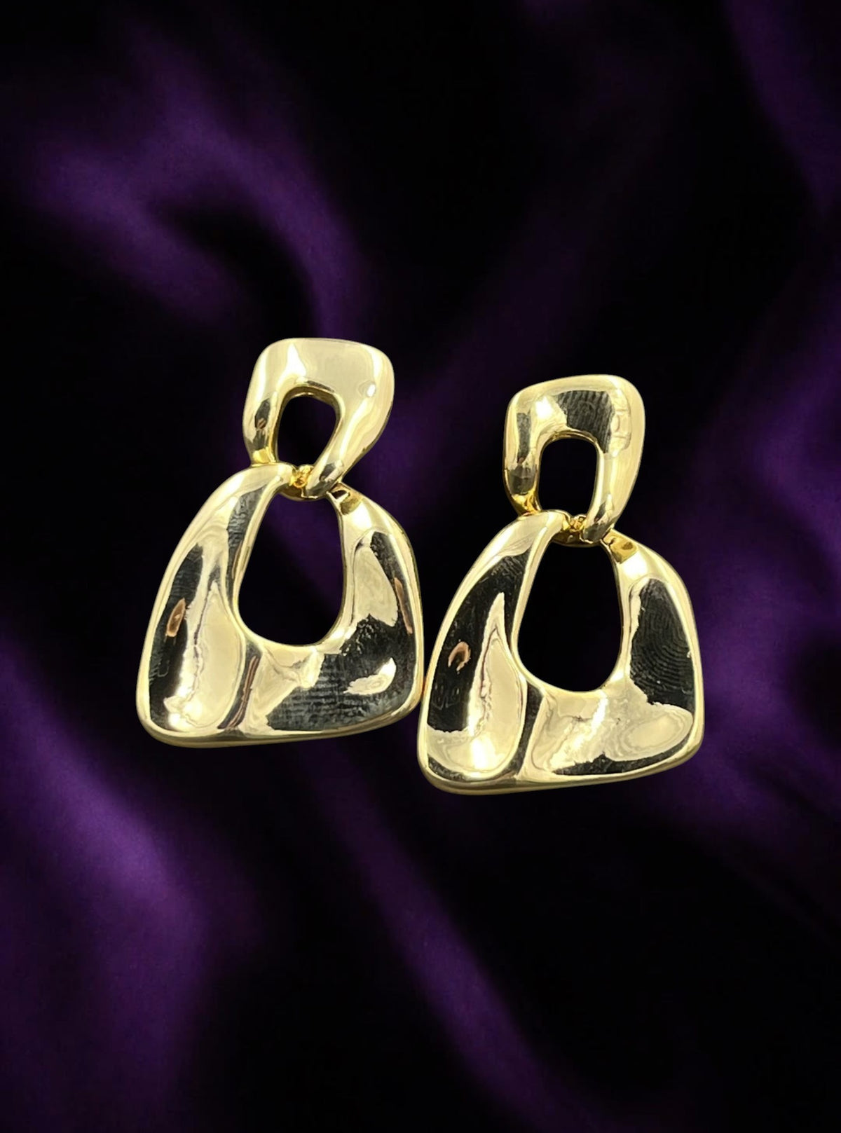 SHE BEAUTY KOREAN GOLD WAVE earrings featuring a polished gold-tone abstract geometric design on purple silk fabric.