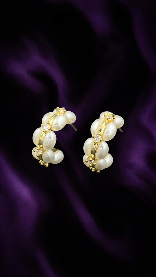 SHE BEAUTY Korean pearl loop earrings featuring white imitation pearls and gold accents on a purple satin background