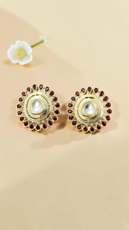 SHE BEAUTY round kundan tops featuring a central clear stone surrounded by red teardrop accents in a gold finish