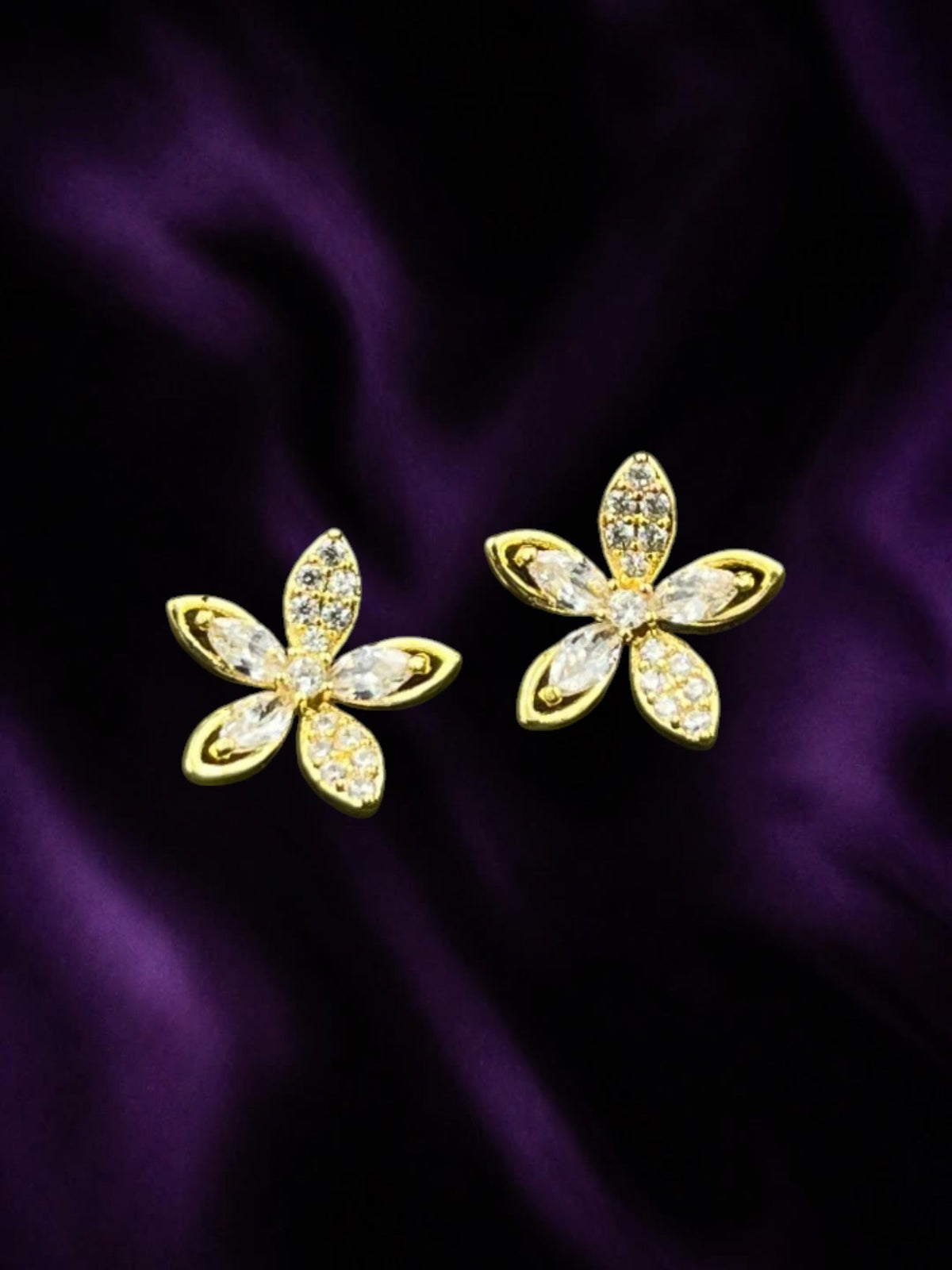 SHE BEAUTY LUXE BLOSSOM gold-tone flower stud earrings with sparkling clear cubic zirconia stones on purple silk