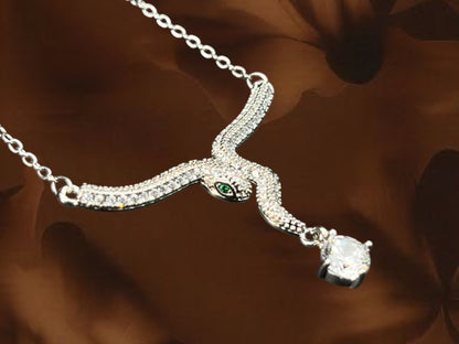 SHE BEAUTY Luxe Serpent pendant necklace featuring silver-tone metal, sparkling crystals, and a green stone eye.