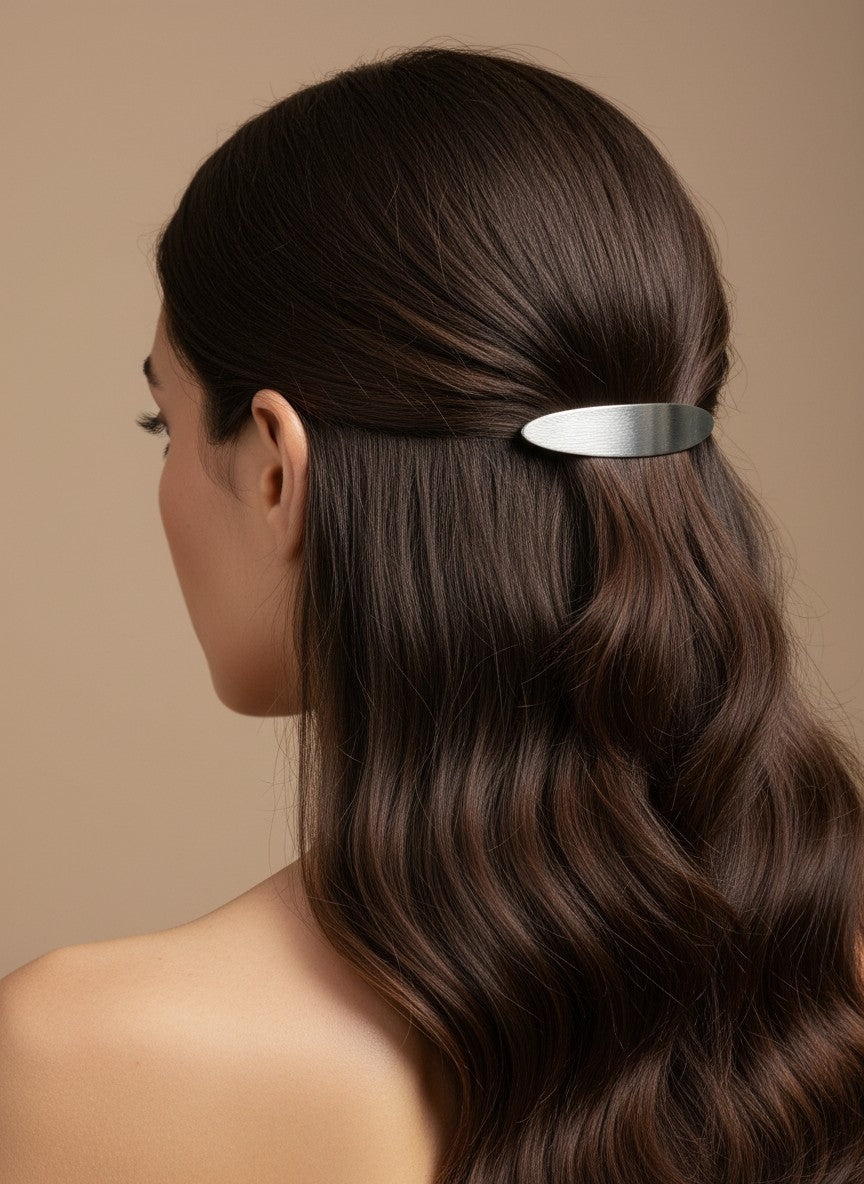 SHE BEAUTY solid metallic barrette in silver worn in long wavy brown hair for a stylish and elegant look.