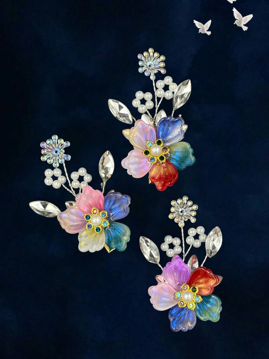 SHE BEAUTY set of three pastel flower hair pins featuring iridescent petals, central pearls, and crystal accents.