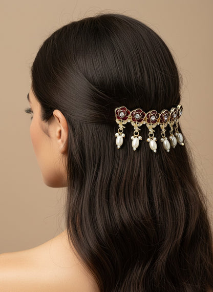 SHE BEAUTY AD rose meenakari barrette with red floral enamel, sparkling stones, and dangling white pearls in hair.