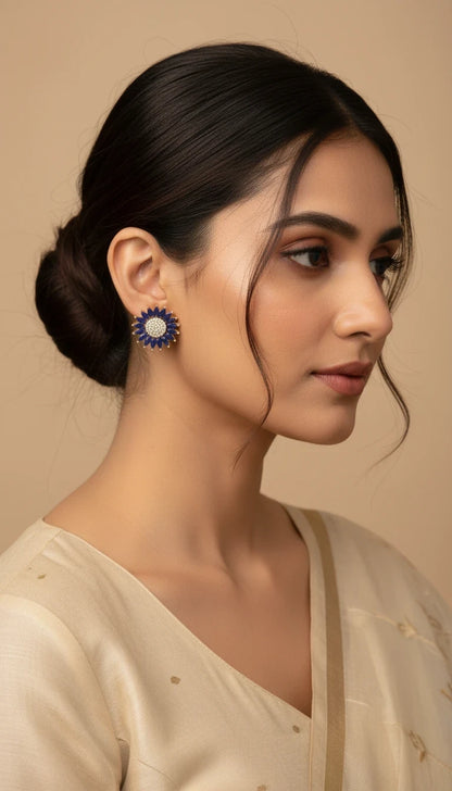 SHE BEAUTY rose gold stud earrings with blue petals and a central cluster of white stones worn by a woman