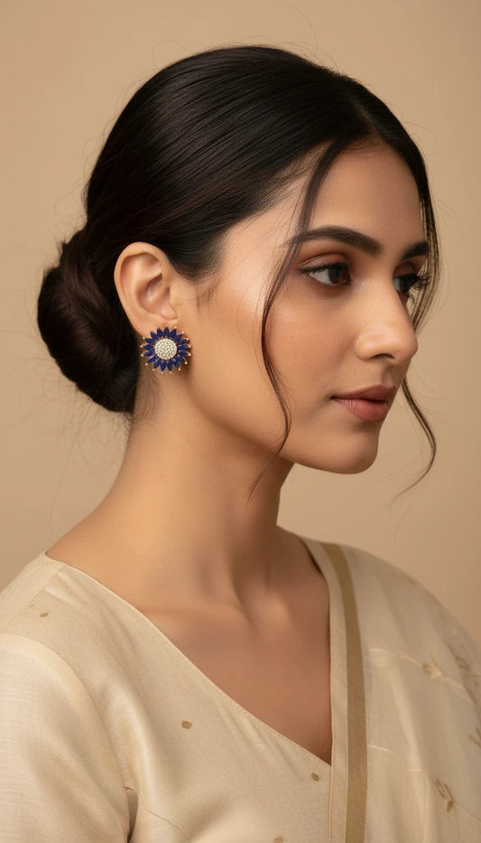 SHE BEAUTY rose gold stud earrings with blue petals and a central cluster of white stones worn by a woman