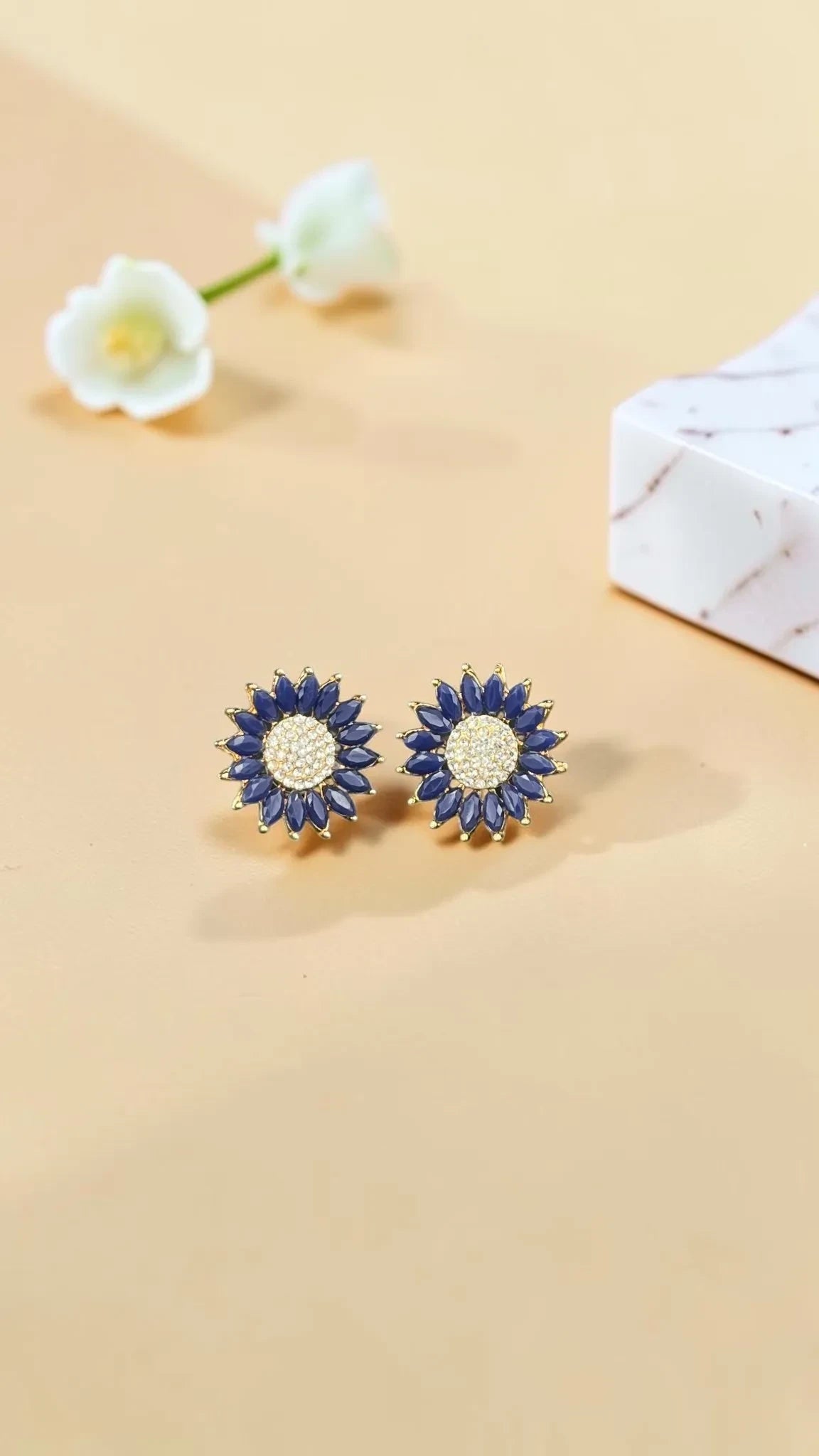 SHE BEAUTY rose gold flower stud earrings with blue marquise stones and a central cluster of sparkling white AD stones