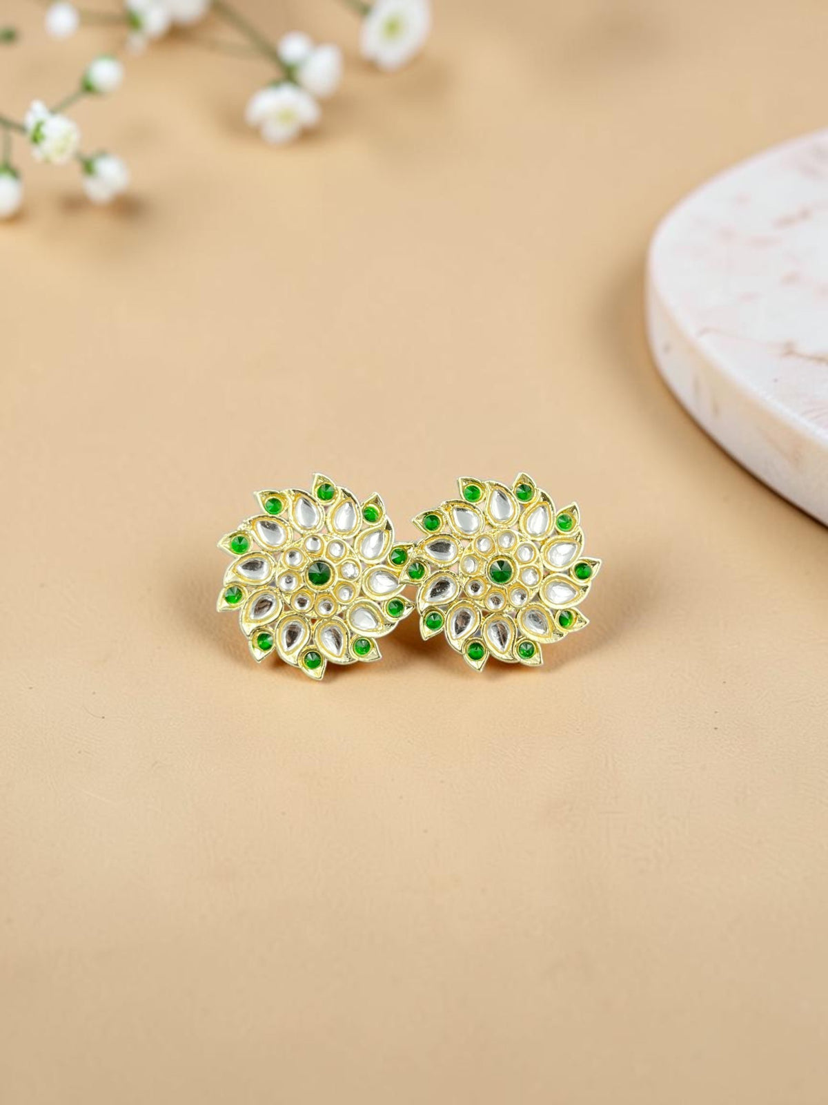 SHE BEAUTY Royal Kundan gold stud earrings featuring intricate floral patterns with green and clear stone accents.