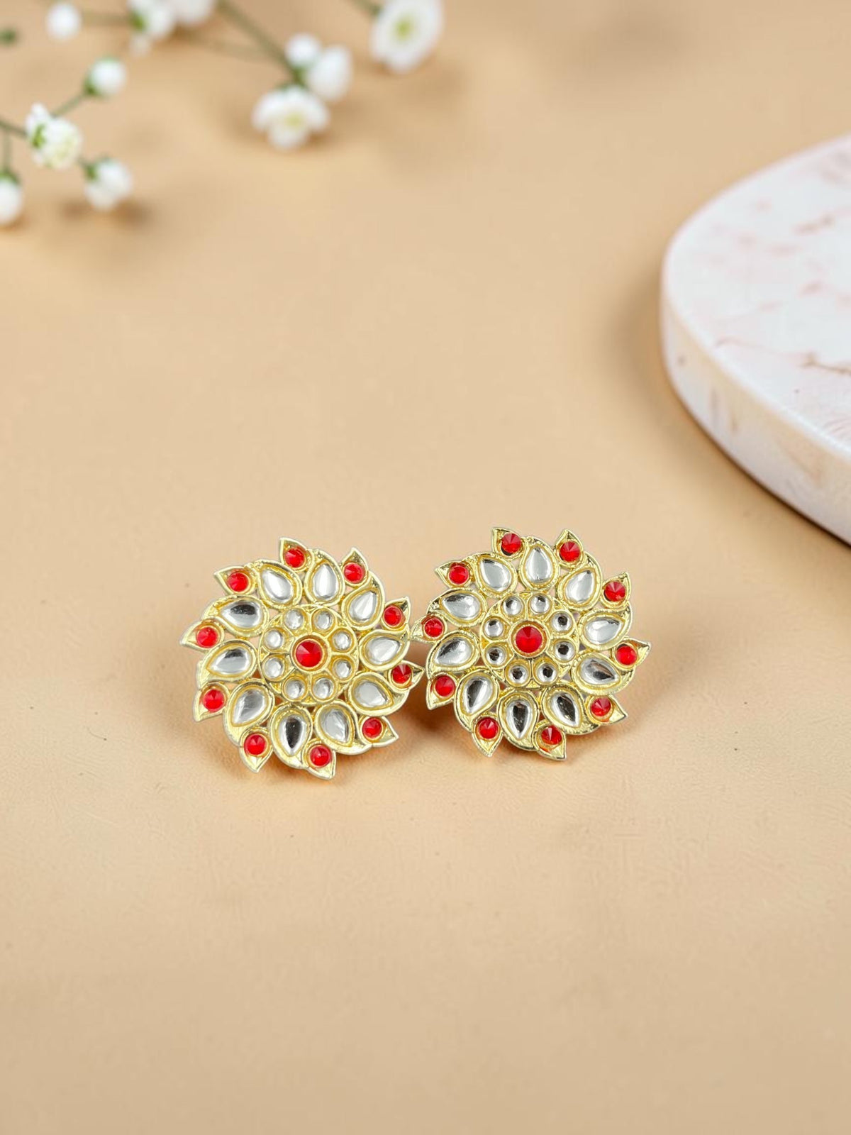SHE BEAUTY Royal Kundan gold stud earrings featuring intricate floral patterns with red stones and white accents