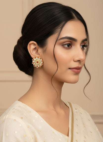 SHE BEAUTY Royal Kundan gold stud earrings with red and white stones worn by a woman in a cream ethnic outfit.