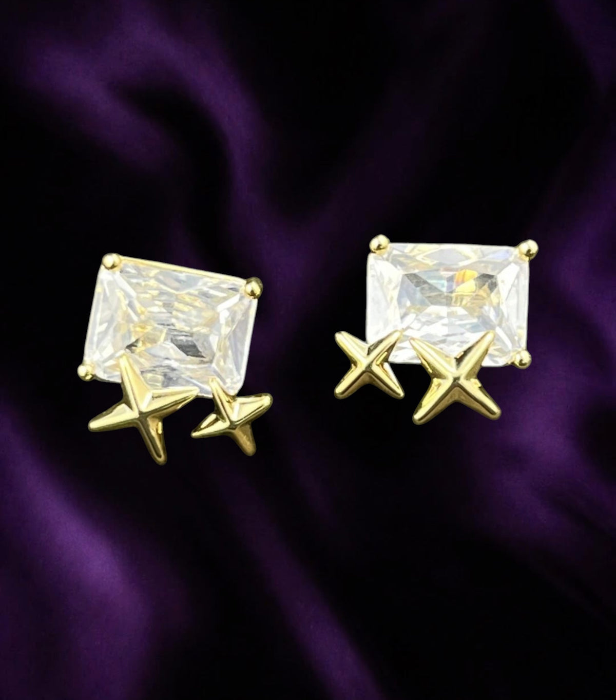 SHE BEAUTY S925 diamond stud earrings featuring a rectangular clear stone and gold star accents on purple fabric.