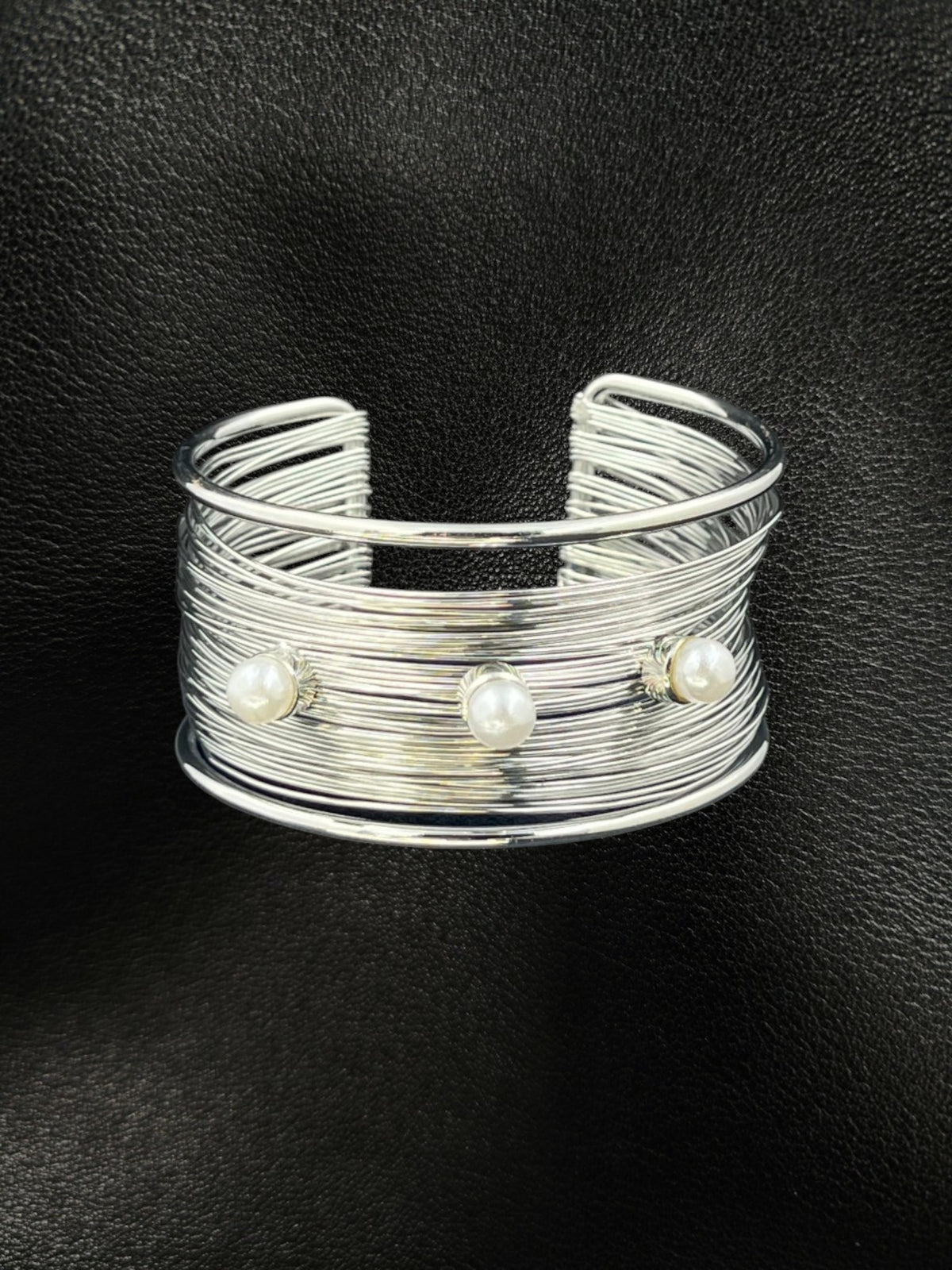 SHE BEAUTY multilayer silver cuff bracelet featuring three white pearls on a textured wire band against black leather.
