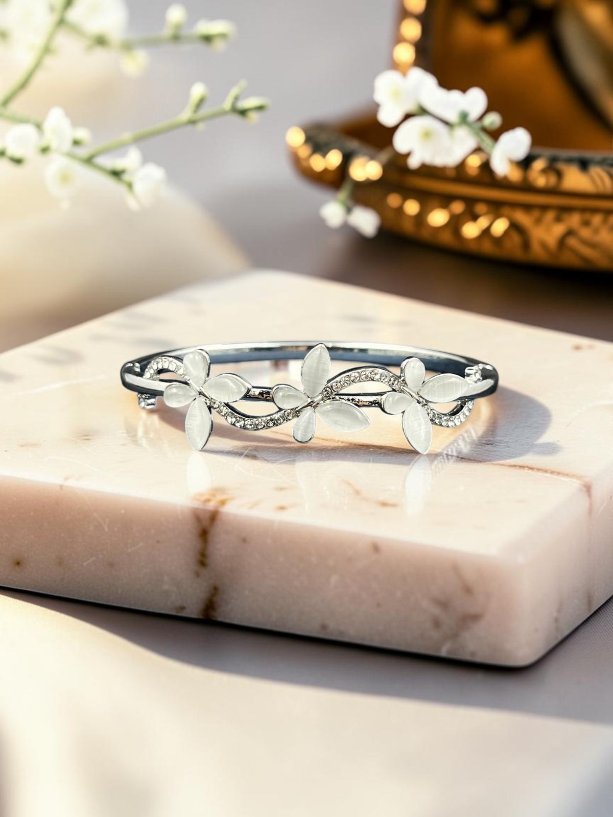 SHE BEAUTY anti-tarnish silver bracelet featuring delicate floral motifs with white zirconia stones on a marble base