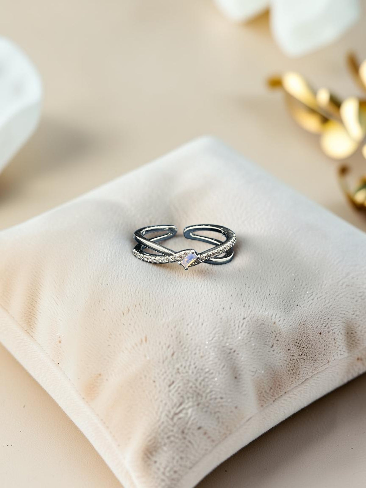SHE BEAUTY sterling girlish ring featuring a delicate crisscross band with sparkling stones on a velvet cushion