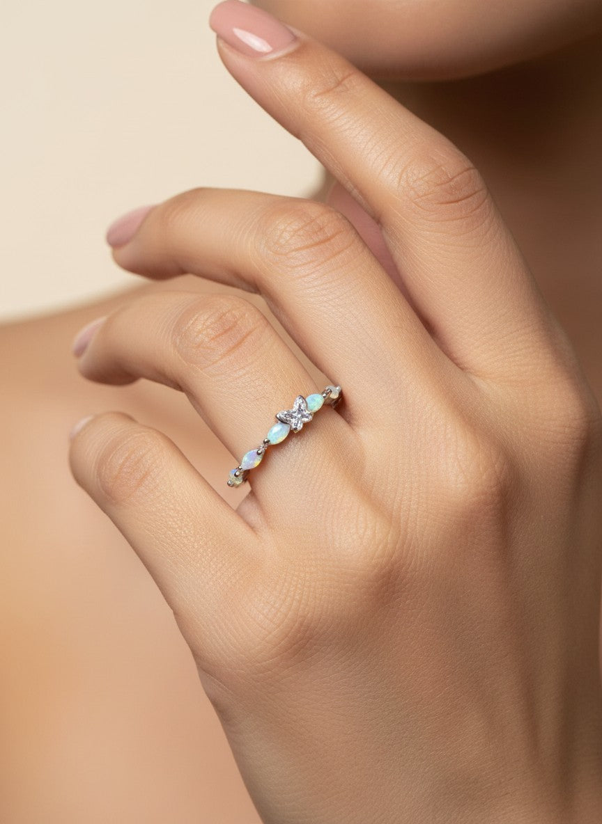 SHE BEAUTY sterling silver ring featuring delicate opal stones and a central butterfly charm on a woman's finger.