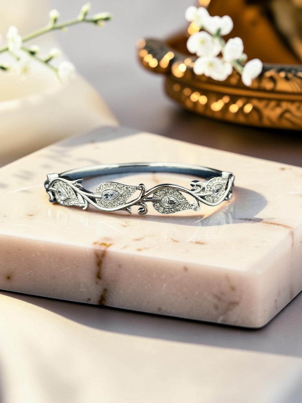 SHE BEAUTY anti-tarnish silver bracelet featuring intricate leaf-shaped zirconia stones on a marble display stand.